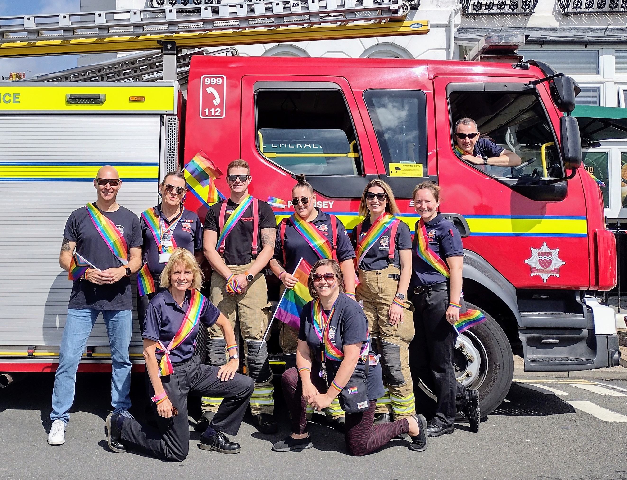 Various members of ESFRS including volunteers and firefighters in front of fire engine at Eastbourne Pride