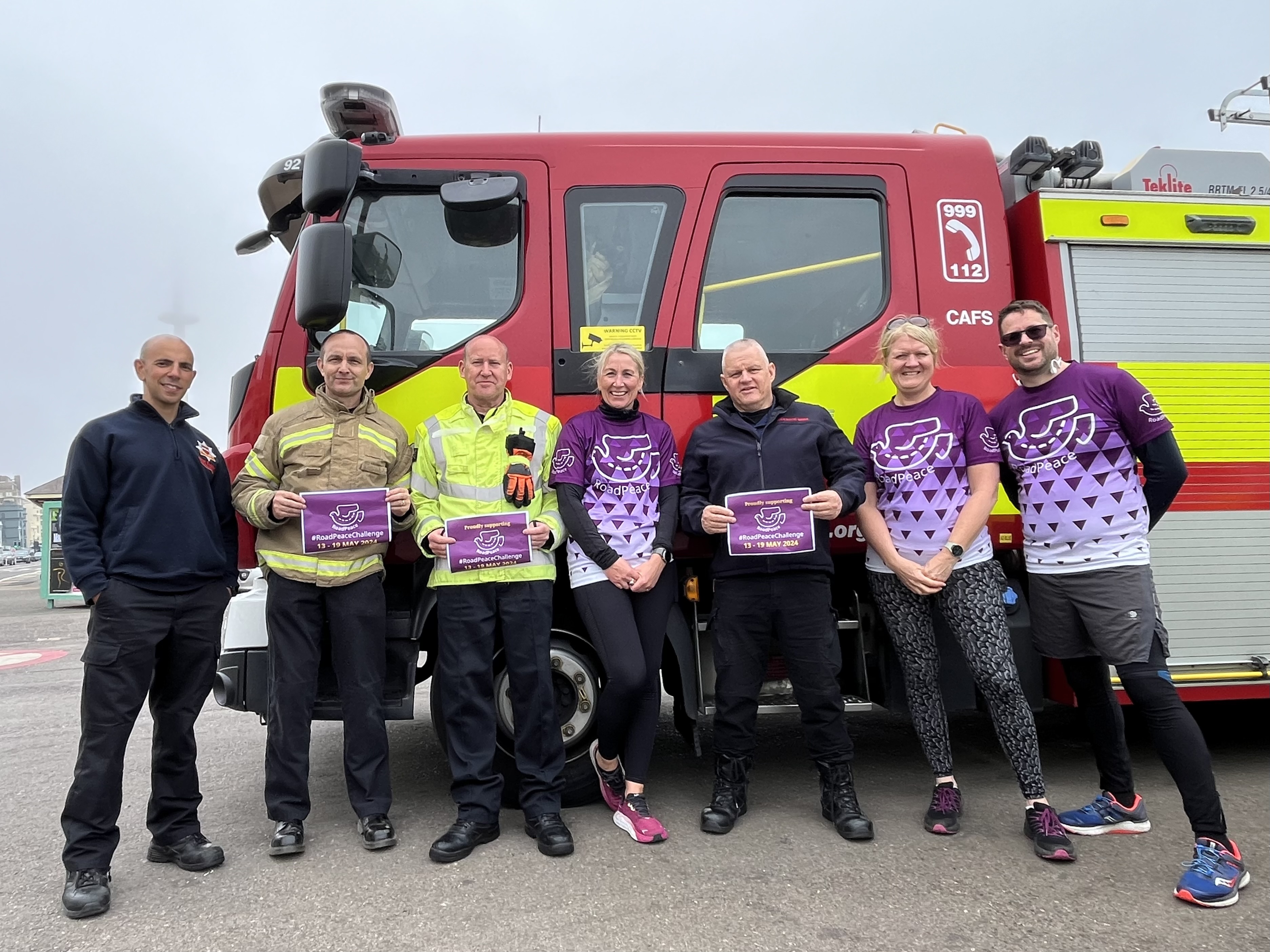 Fire and Rescue staff in front of Fire engine holding RoadPeace challenge signs