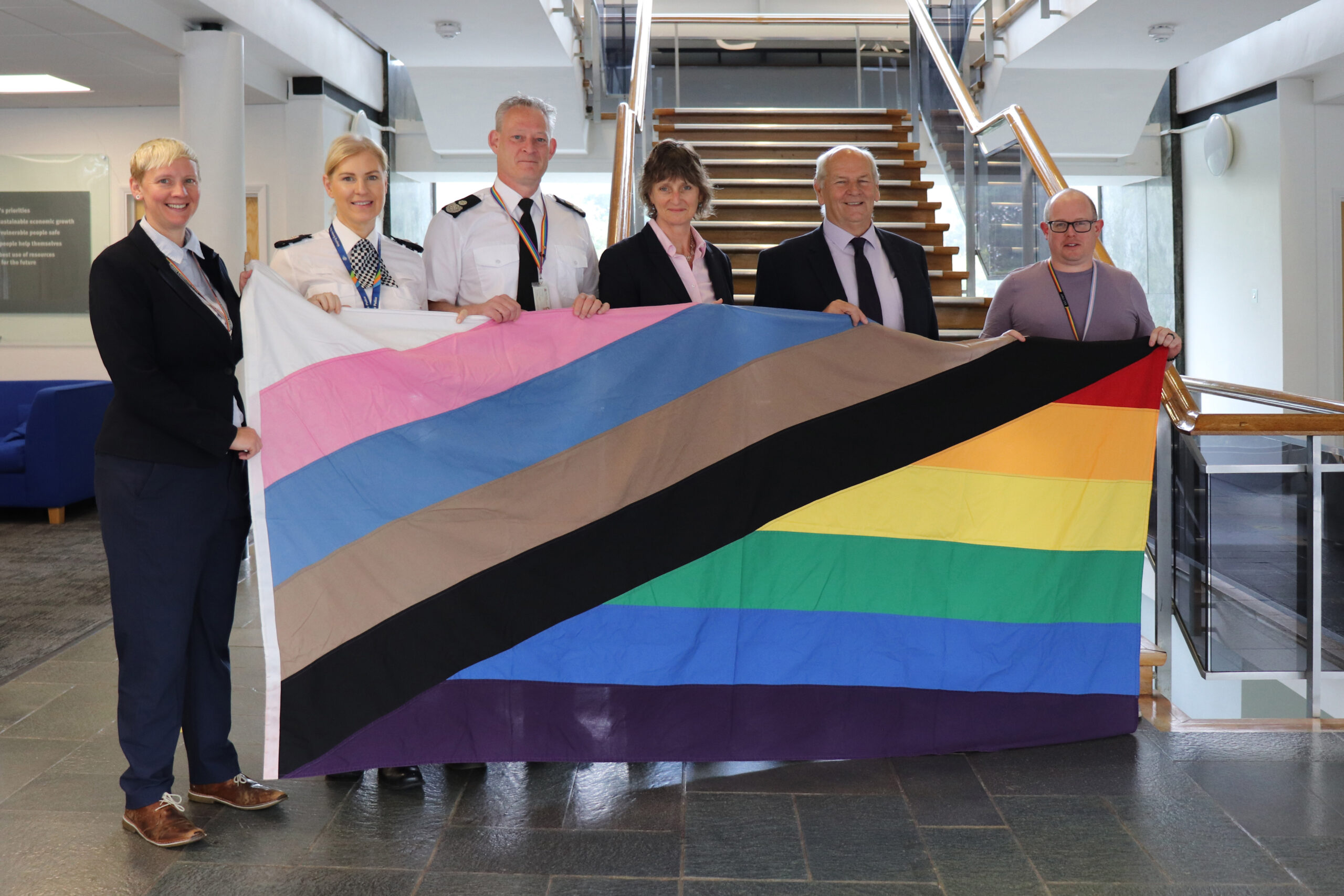 Photo of 6 people holding a Pride flag