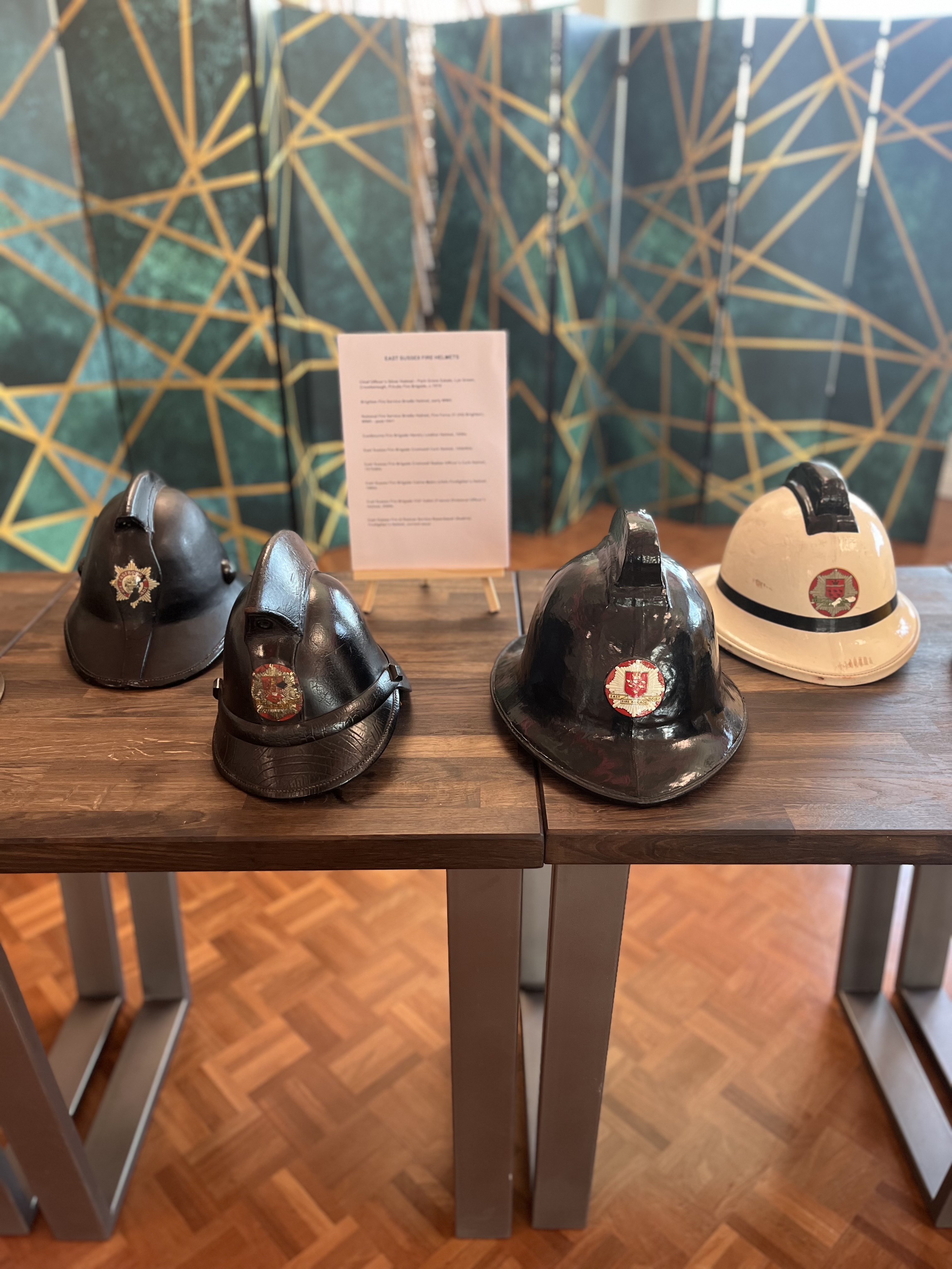 Four historical fire helmets on wooden display table