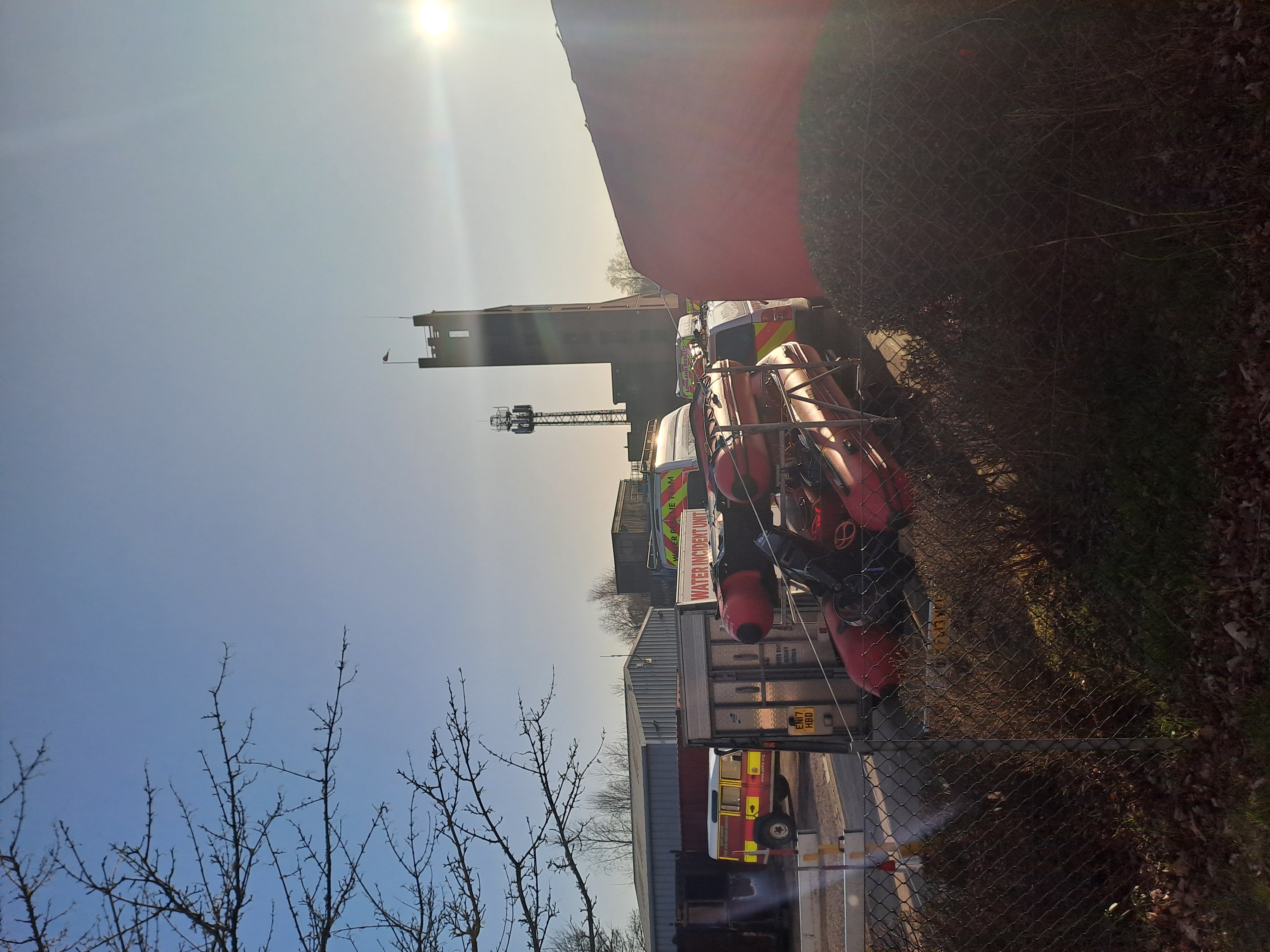 Silouhette of a fire drill tower and a fire and rescue search boat and vehicles in a yard