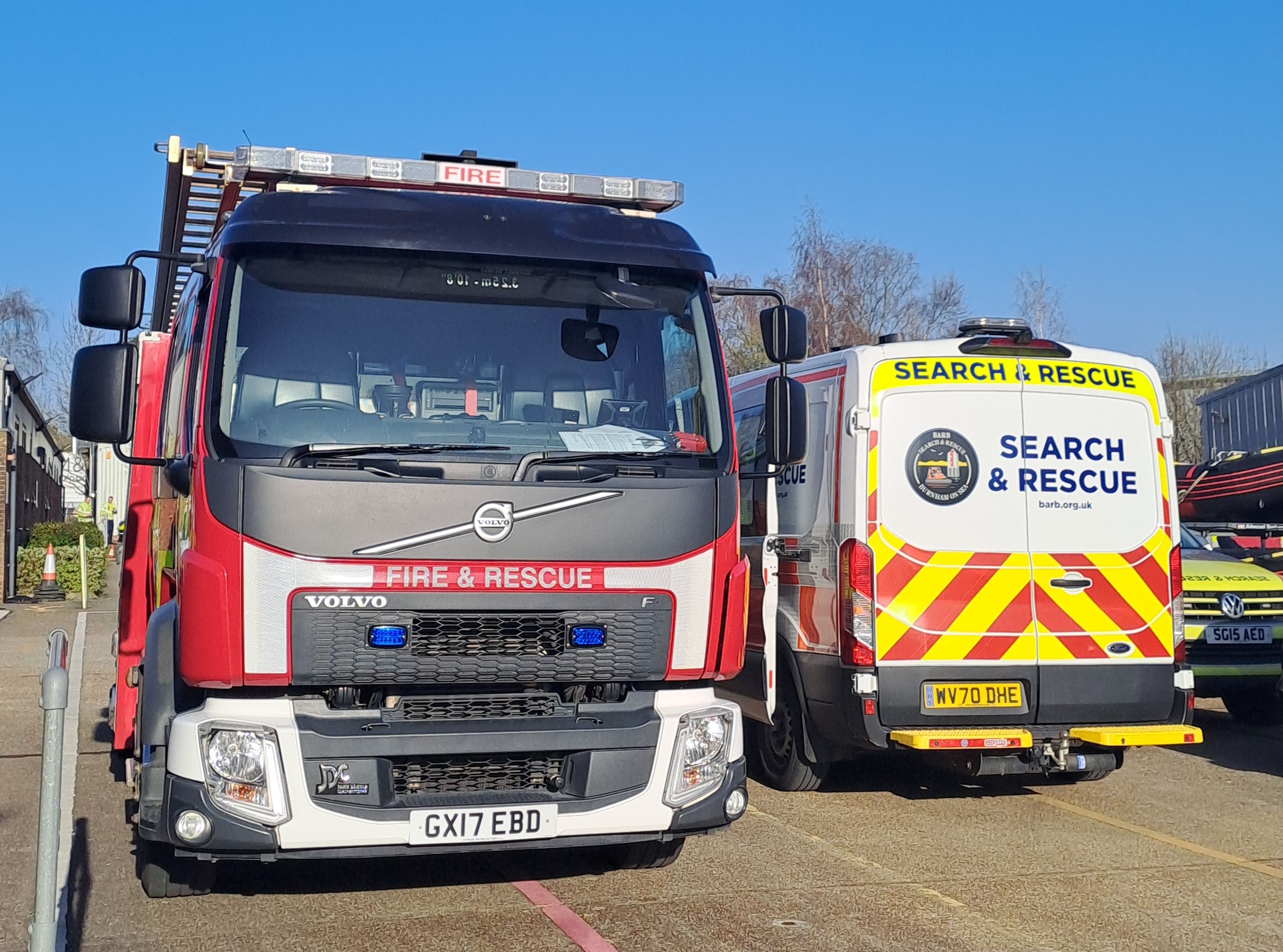 Front of red fire engine next to a white search and rescue van
