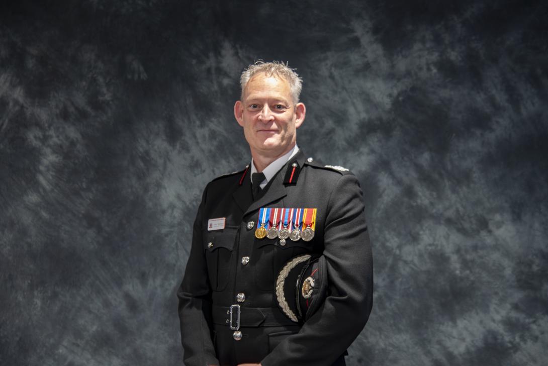 Photo of Mark Matthews in uniform with medals in front of dark grey backdrop