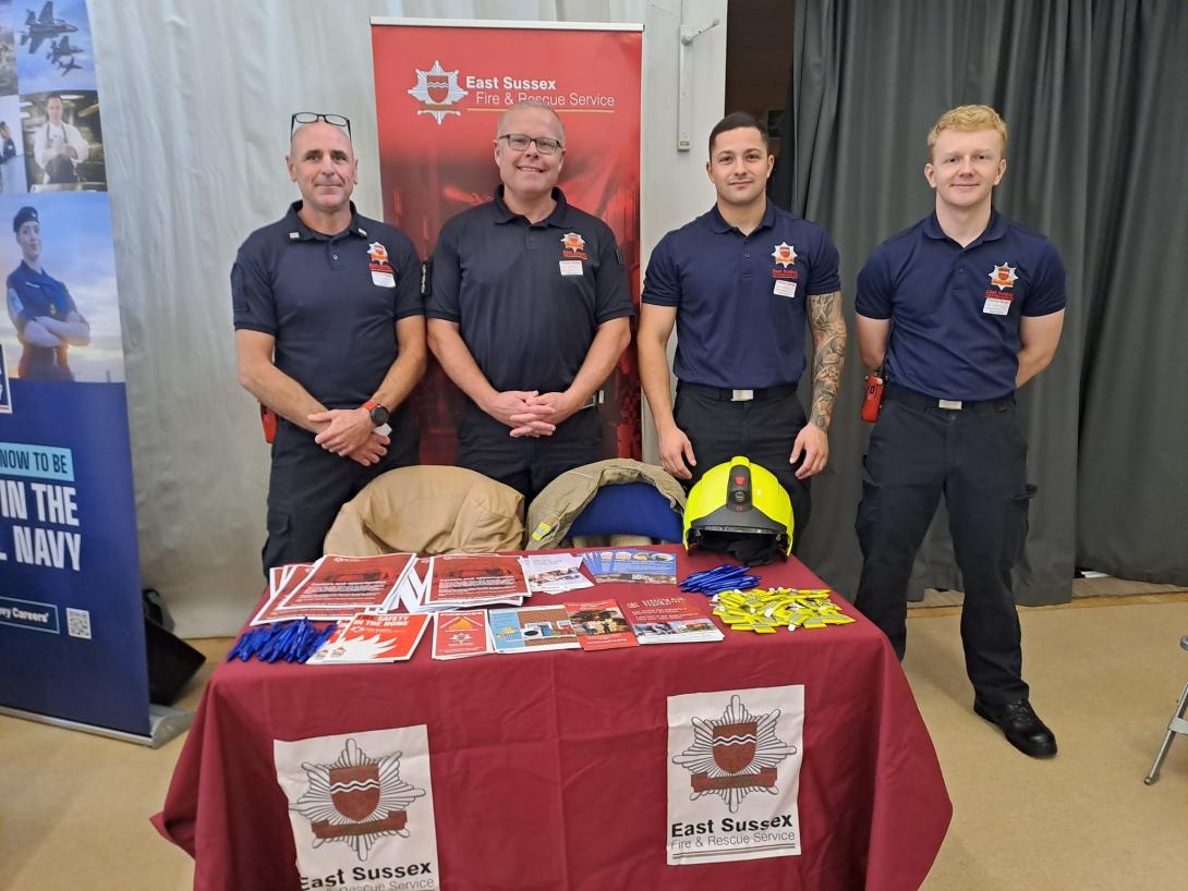 4 ESFRS firefighters standing behind a desk for a Freshers event